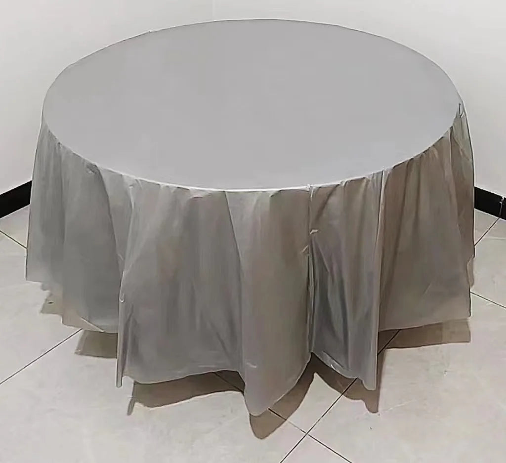 A round table covered with a white plastic disposable tablecloth on a light floor.