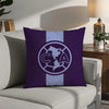 A purple decorative pillow case featuring a white circular logo with the letters CA inside, set against a light gray sofa.