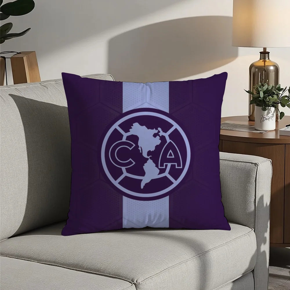 A purple decorative pillow case featuring a white circular logo with the letters CA inside, set against a light gray sofa.