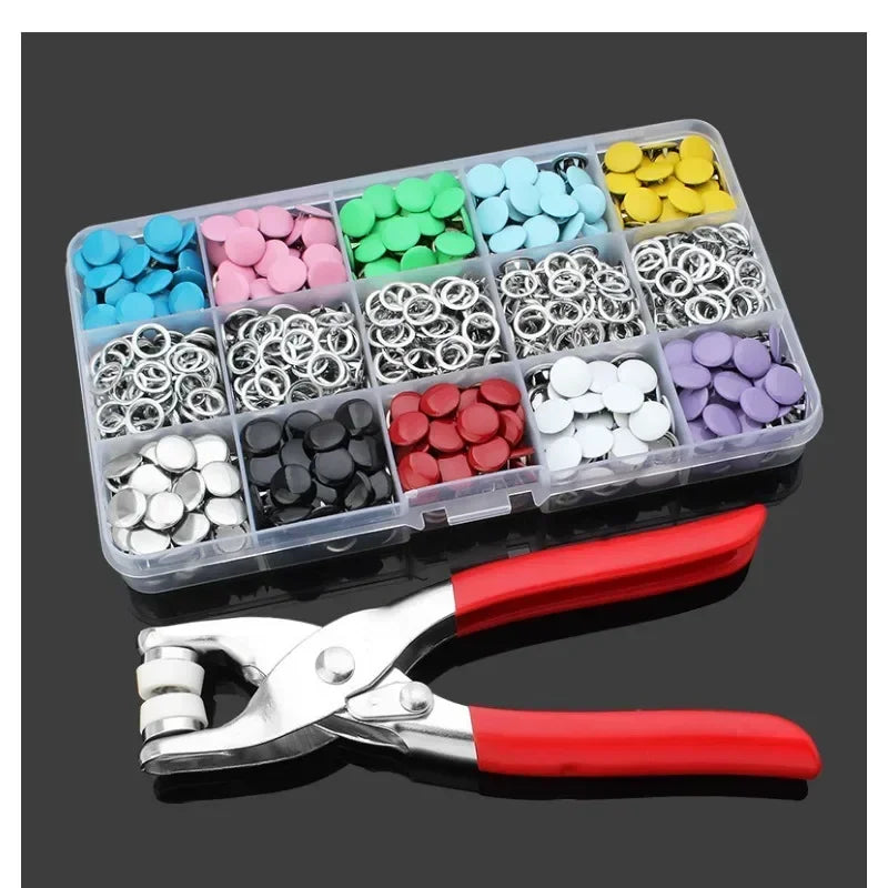 A plastic tray holds various colorful metal sewing buttons in different shades of blue, pink, green, and yellow.