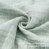 A close-up of a soft, light gray cotton fabric draped and folded to show its texture.