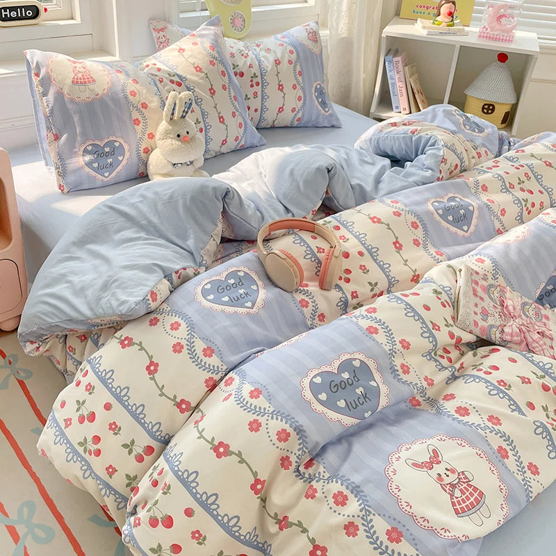 A set of light blue and white microfiber duvet covers and pillowcases featuring a pattern of hearts, flowers, and rabbits.