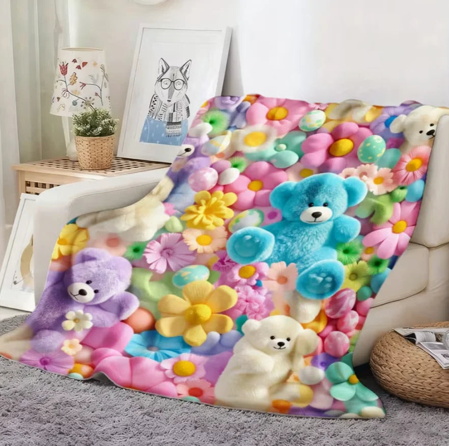 A colorful flannel blanket featuring a floral print with various teddy bears and flowers.