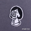 Black and white embroidered patch depicting a stylized skull face for iron-on use