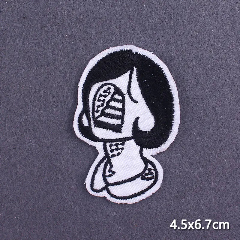 Black and white embroidered patch depicting a stylized skull face for iron-on use