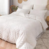 White bohemian grid tufted duvet cover set with layered pillows on a bed.