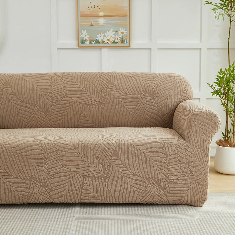 A beige sofa slipcover featuring a woven jacquard leaves pattern on a light floor.