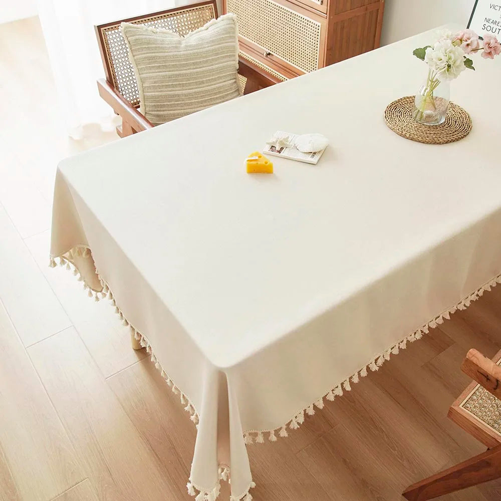 A white tablecloth is set for a meal with a yellow item and a small floral arrangement on a wooden table.