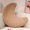 A beige moon-shaped throw pillow resting on a white surface.