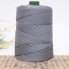 A spool of gray 3mm ice rope crochet yarn for crafting, coiled and resting on a woven surface.