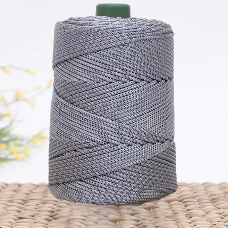 A spool of gray 3mm ice rope crochet yarn for crafting, coiled and resting on a woven surface.