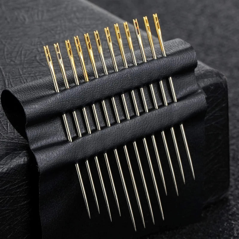 A set of stainless steel self-threading sewing needles is shown laid out on black leather.