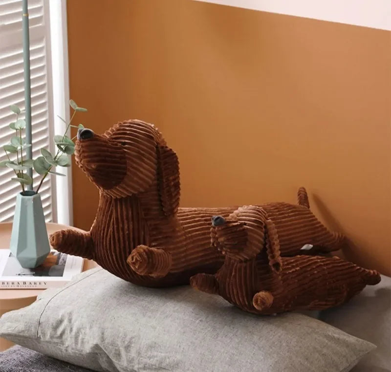 A brown corduroy dachshund body pillow resting on a gray cushion against an orange wall.