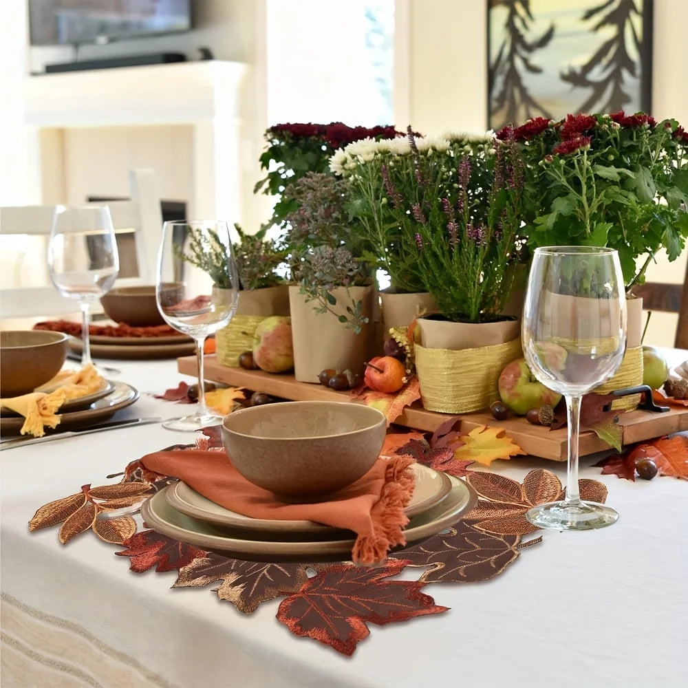 A rustic farmhouse maple leaf table runner laid on a white tablecloth with autumnal foliage and floral arrangements.