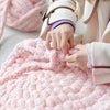 A person is holding and examining a fluffy pink hand-knitted wool finger line scarf.