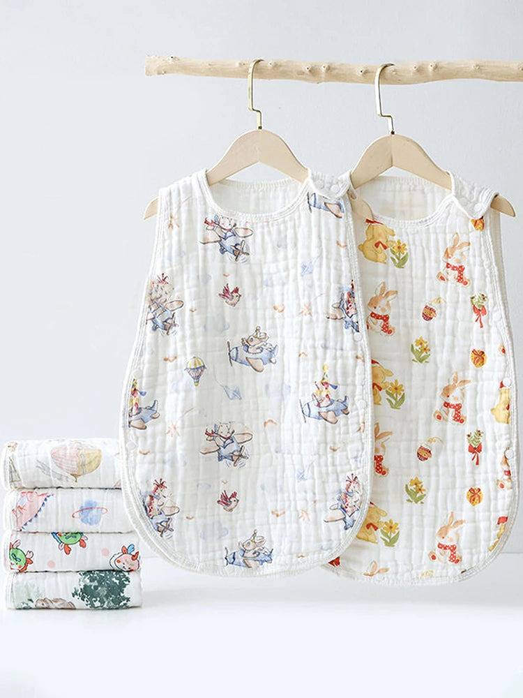 A white quilted baby sleeping bag with floral embroidery is displayed on a wooden hanger.