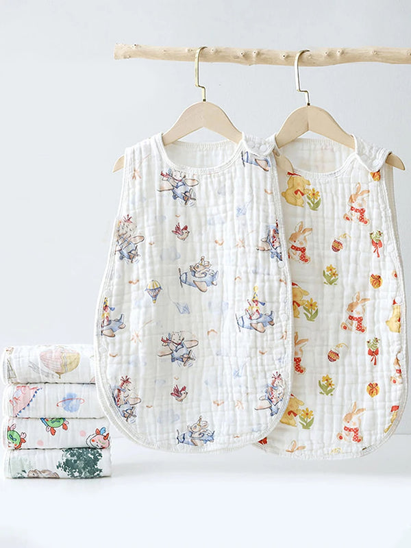 A white quilted baby sleeping bag with floral embroidery is displayed on a wooden hanger.