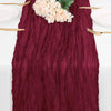 Burgundy cheesecloth table runner with white flowers and gold cutlery for rustic decor