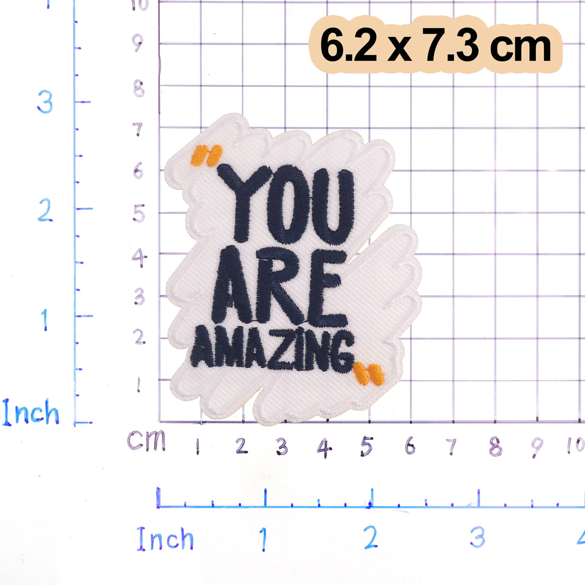 White embroidered patch with black text YOU ARE AMAZING and small orange accents on a grid background.