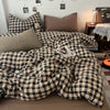 A plaid duvet cover set featuring black and tan checks is displayed on a bed with pillows.