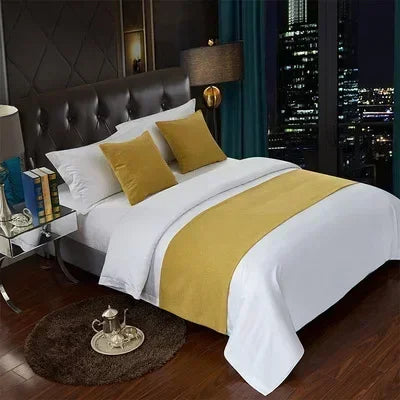 A luxurious bedroom featuring a bed with white linens and gold accents, set against a dark wall and a cityscape view.