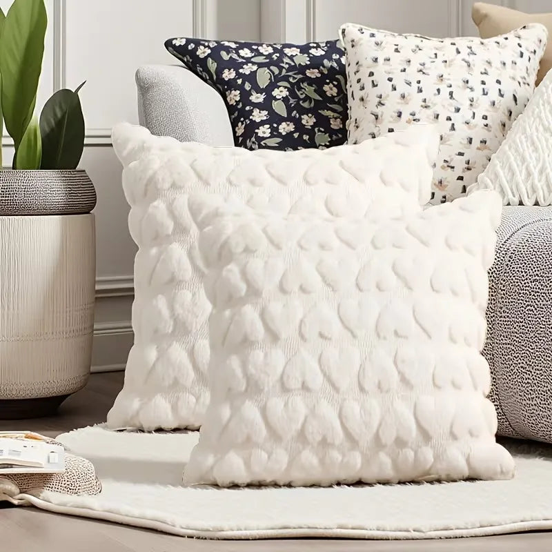 A collection of white and dark floral patterned plush cushion covers displayed on a light rug.