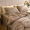 A bed dressed with a princess ruffle cotton bedding set featuring beige and cream pillows and sheets.