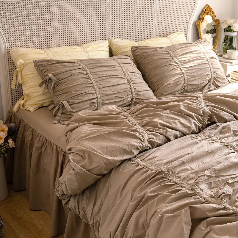 A bed dressed with a princess ruffle cotton bedding set featuring beige and cream pillows and sheets.