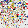 A colorful mix of clear glass rhinestones and sequins scattered on a white background for DIY crafts.