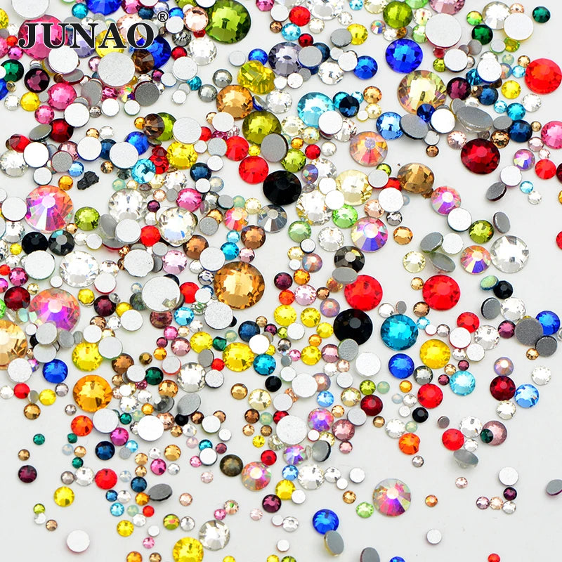 A colorful mix of clear glass rhinestones and sequins scattered on a white background for DIY crafts.