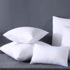 A stack of white breathable square core cushions resting on a gray surface.