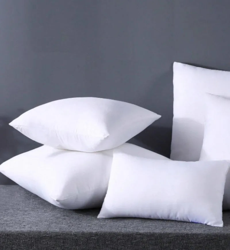 A stack of white breathable square core cushions resting on a gray surface.