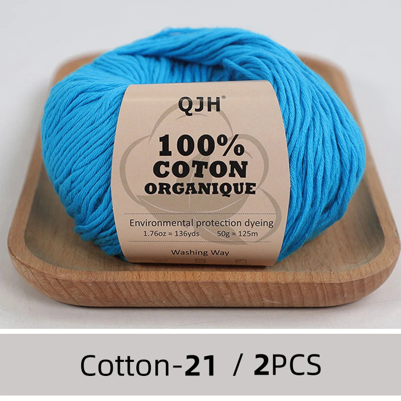 A ball of bright blue 100% organic cotton yarn labeled QJH for knitting and crochet
