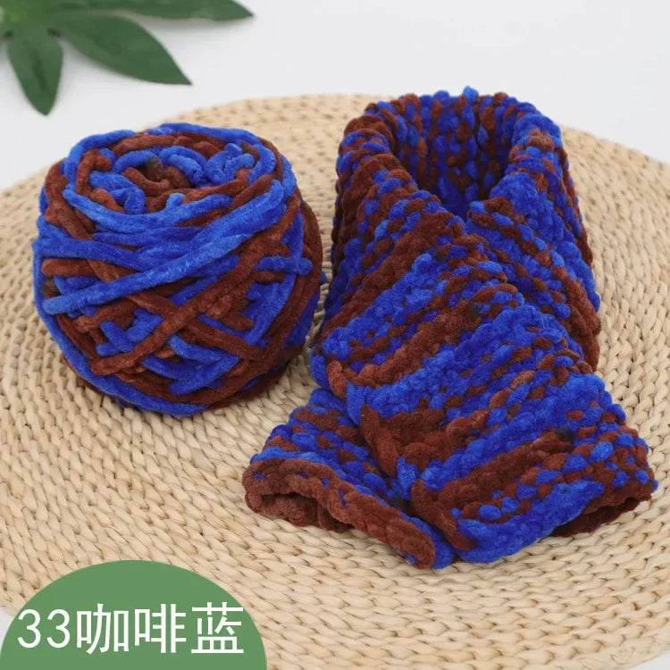 A rolled piece of blue and brown chenille knitting yarn resting on a woven mat.