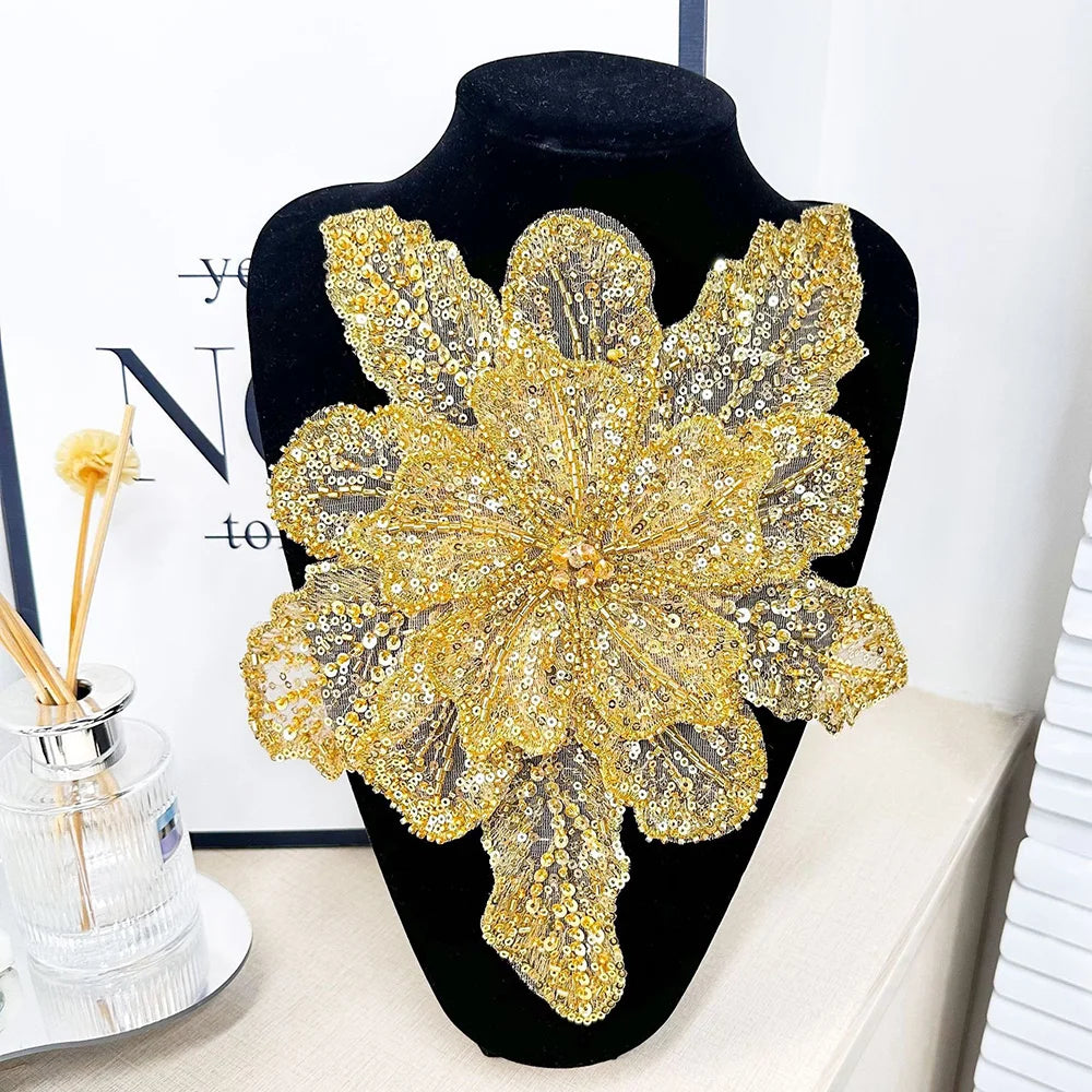 A large, intricate gold sequin lace applique fabric patch shaped like a flower displayed on a black mannequin.