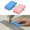 A hand is using a blue magnetic seam guide with a stitch gauge on a gray fabric for sewing.