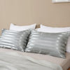 Silver and white striped pillow covers displayed on a bed with a neutral background.