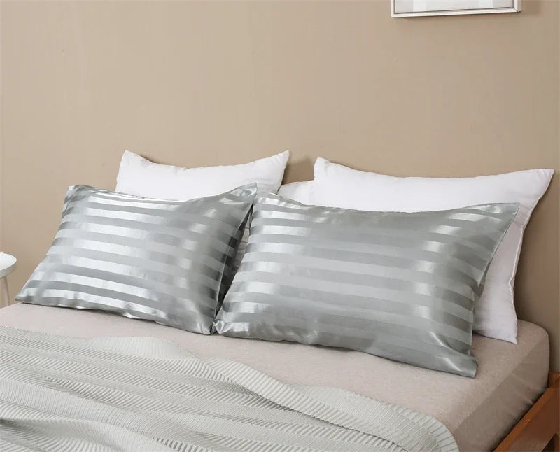 Silver and white striped pillow covers displayed on a bed with a neutral background.