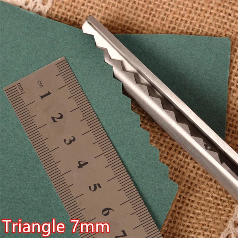Stainless steel triangle-tipped sewing shears shown next to a ruler on a brown fabric background.