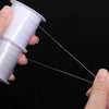 A hand is pulling a thin white nylon beading thread from a spool for jewelry making.