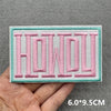 Pink embroidered slogan patches spelling HOWDY on a light green fabric background