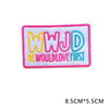 Pink embroidered letter patch spelling out WWJD with the text WouldLoveFirst in yellow and blue thread.
