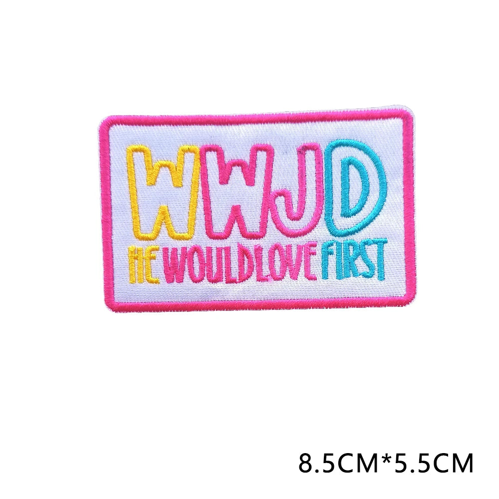 Pink embroidered letter patch spelling out WWJD with the text WouldLoveFirst in yellow and blue thread.