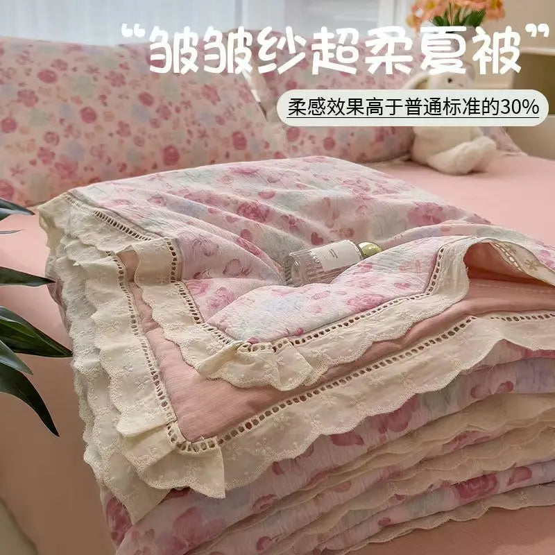 Pink and white floral print quilt blanket folded on a bed