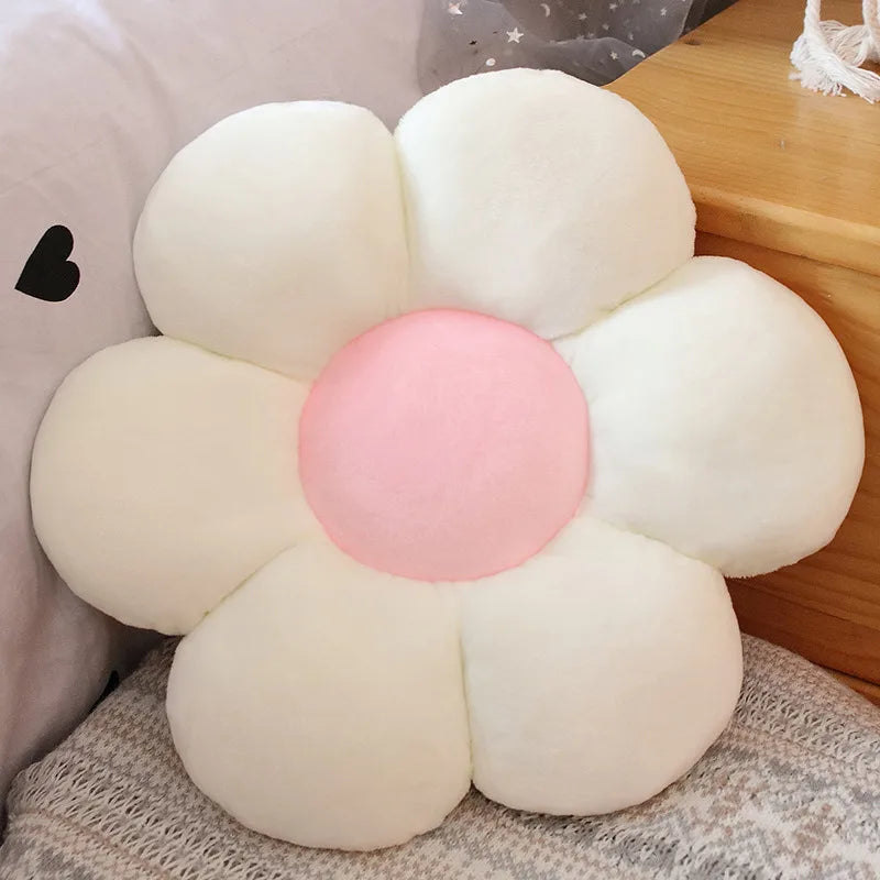A white sunflower plush flower cushion with a pink center, resting on a light gray textured surface.