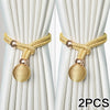Two sets of gold-colored fabric tiebacks with knotted cords and spherical tassels against a light background