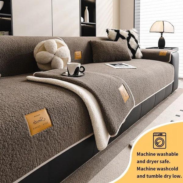A beige multi-functional fleece sofa mat with decorative pillows and a folded throw blanket shown on a modern sofa.