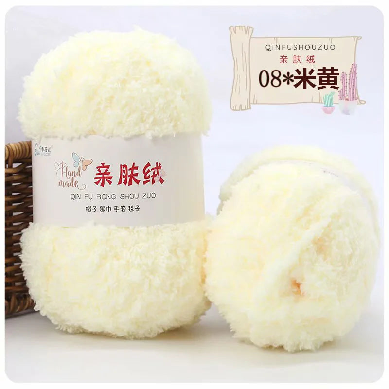 A white ball of soft coral velvet yarn is displayed next to its packaging and a wooden stick.