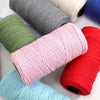 A collection of various colored yarn skeins, including pink, red, green, and blue, arranged on a white surface.