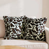 A set of two leopard print throw pillow covers resting on a light-colored sofa.
